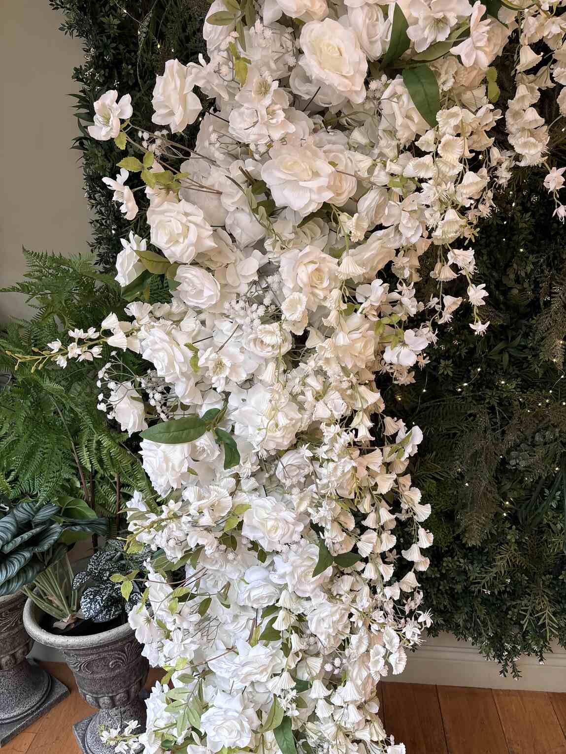 Side column of floral arch with cascading white roses, hydrangeas and trailing flowers