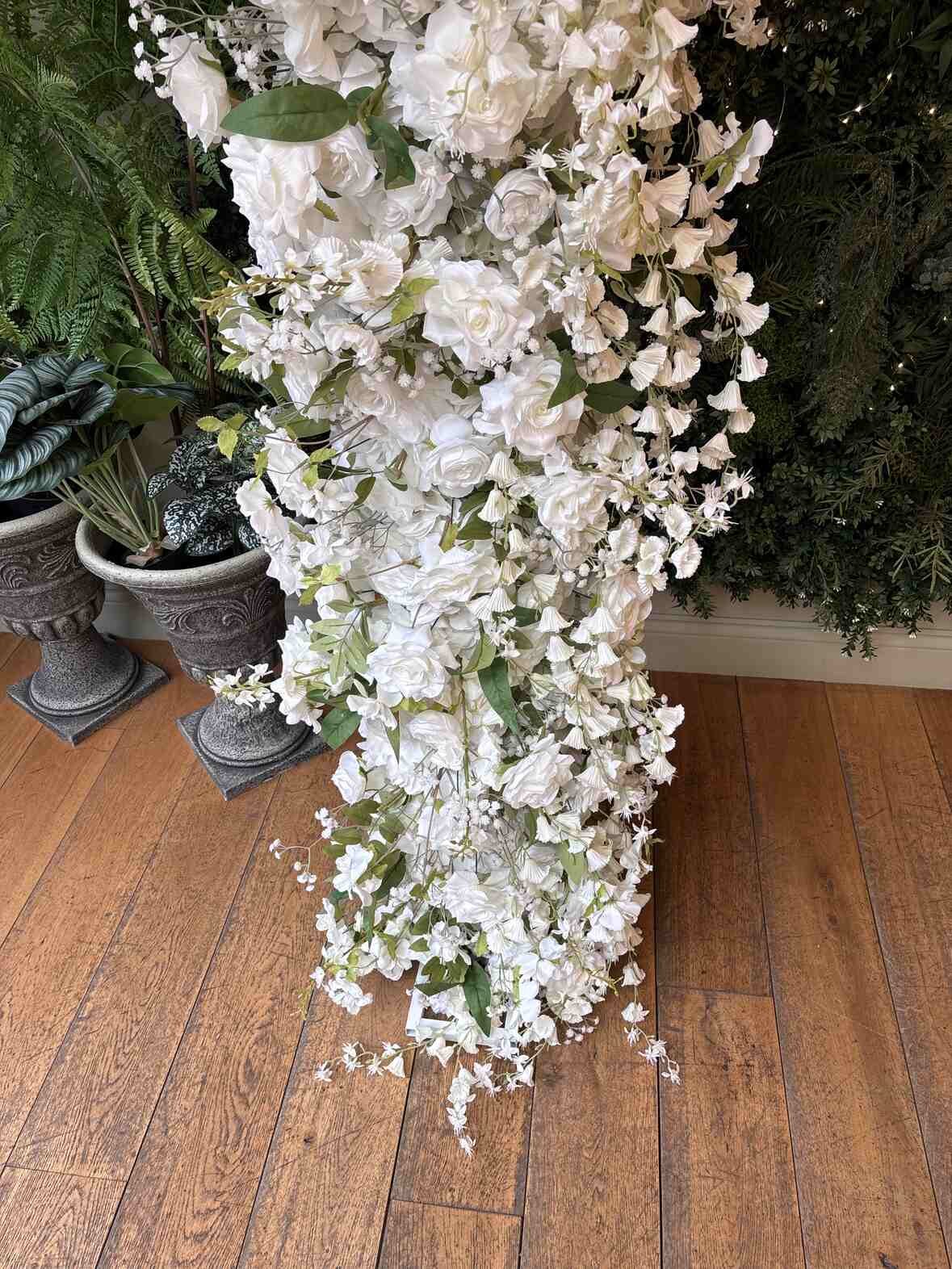 Left column of floral arch with lush white blooms and green foliage