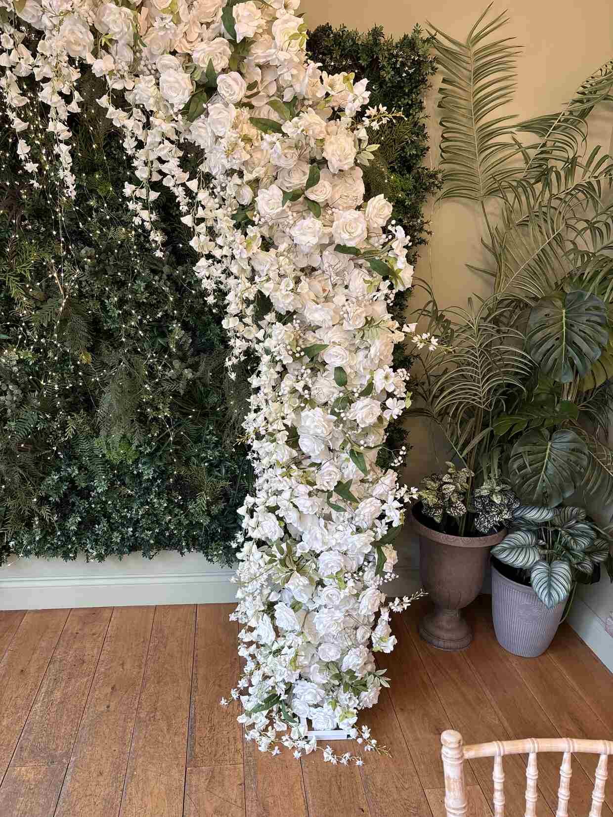 Arch pillar close-up showing dense white roses and trailing wisteria blooms